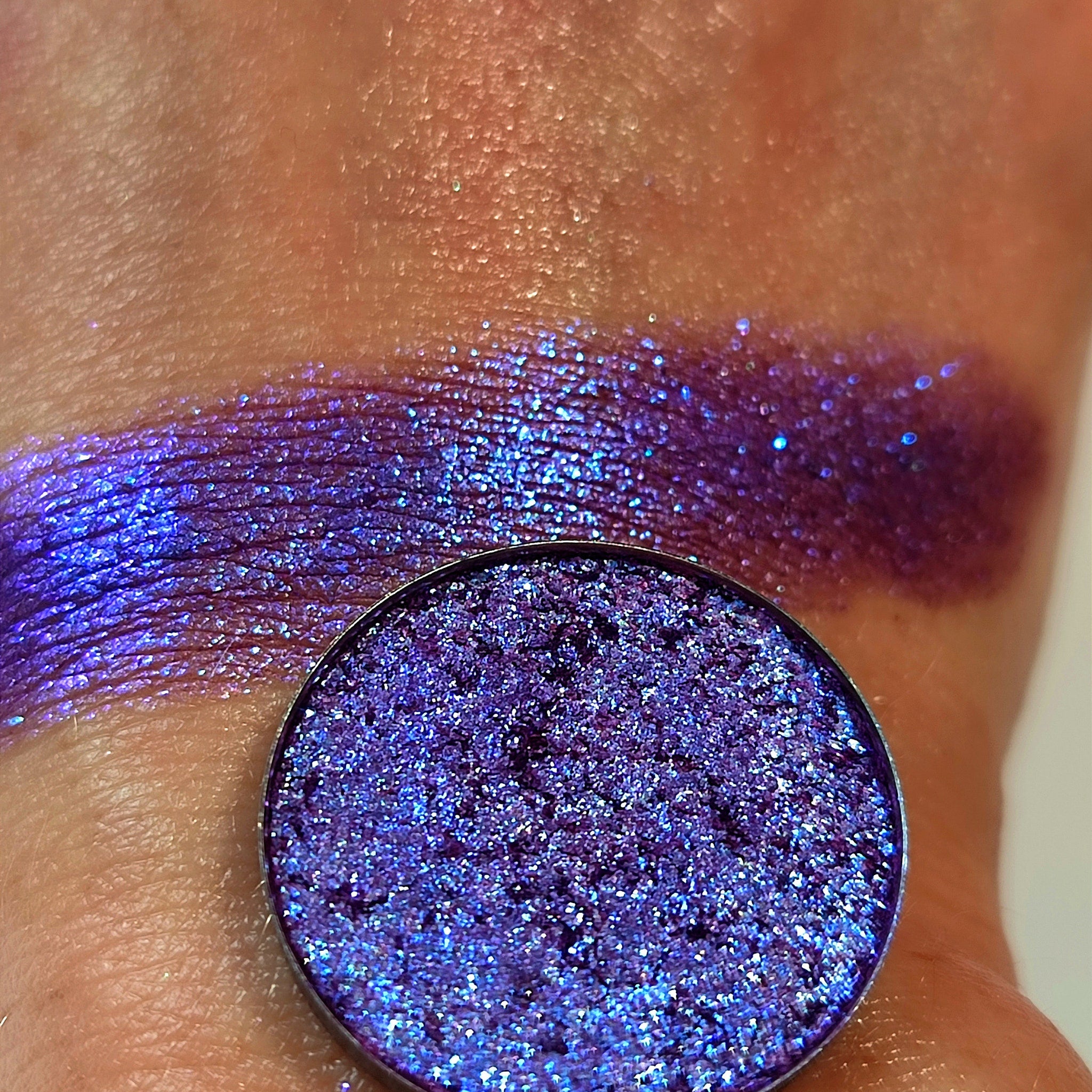 Eye shadow, purple shimmer, swatched on skin, circular compact visible
