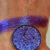 Eye shadow, purple shimmer, swatched on skin, circular compact visible