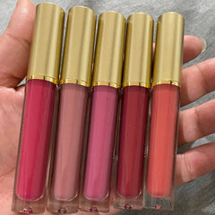 Lip gloss tubes with gold caps, various shades of pink and red, held in hand