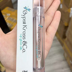 Lip gloss oil, clear tube, white label, Gypsii Kross & Co. branding, held in hand
