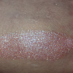 Close-up of fingertips applying shimmery bronze eye shadow to eyelid with blending brush