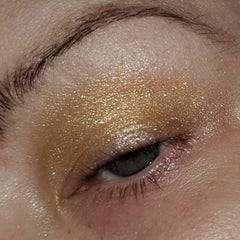 Eye shadow with gold shimmer, glitter, and brown skin around eye.