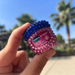 Vaseline lip therapy container with pink and blue crystal embellishments, held in hand