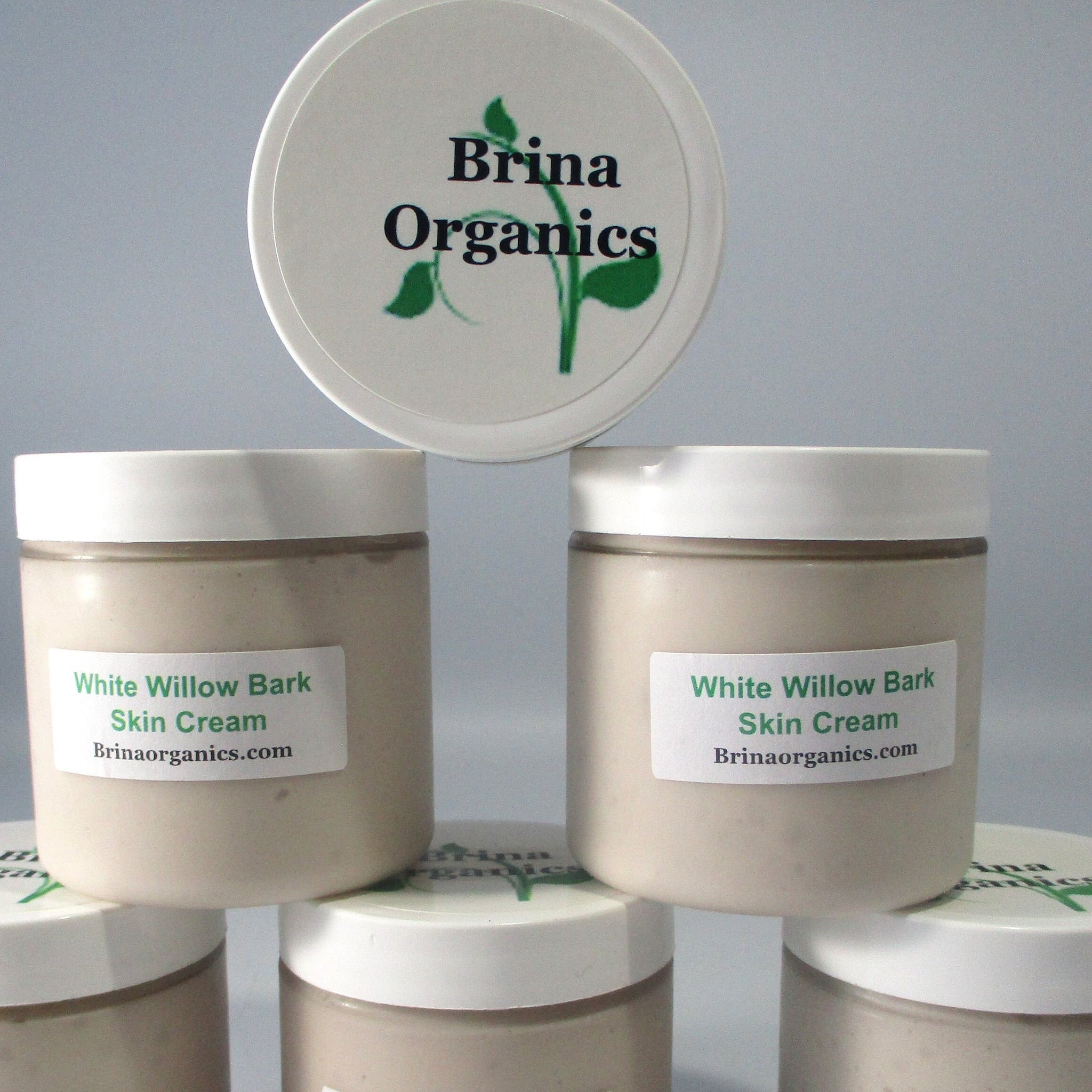 Skin cream jars with white lids, beige cream, and Brina Organics label visible