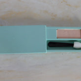 Eyeshadow compact in pale pink and teal, with applicator, open showing product