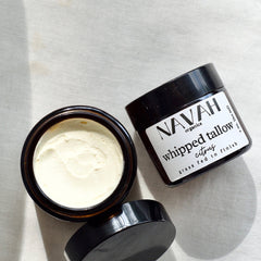 Hand scooping whipped tallow balm from a glass jar, showing its rich creamy texture for skin application
