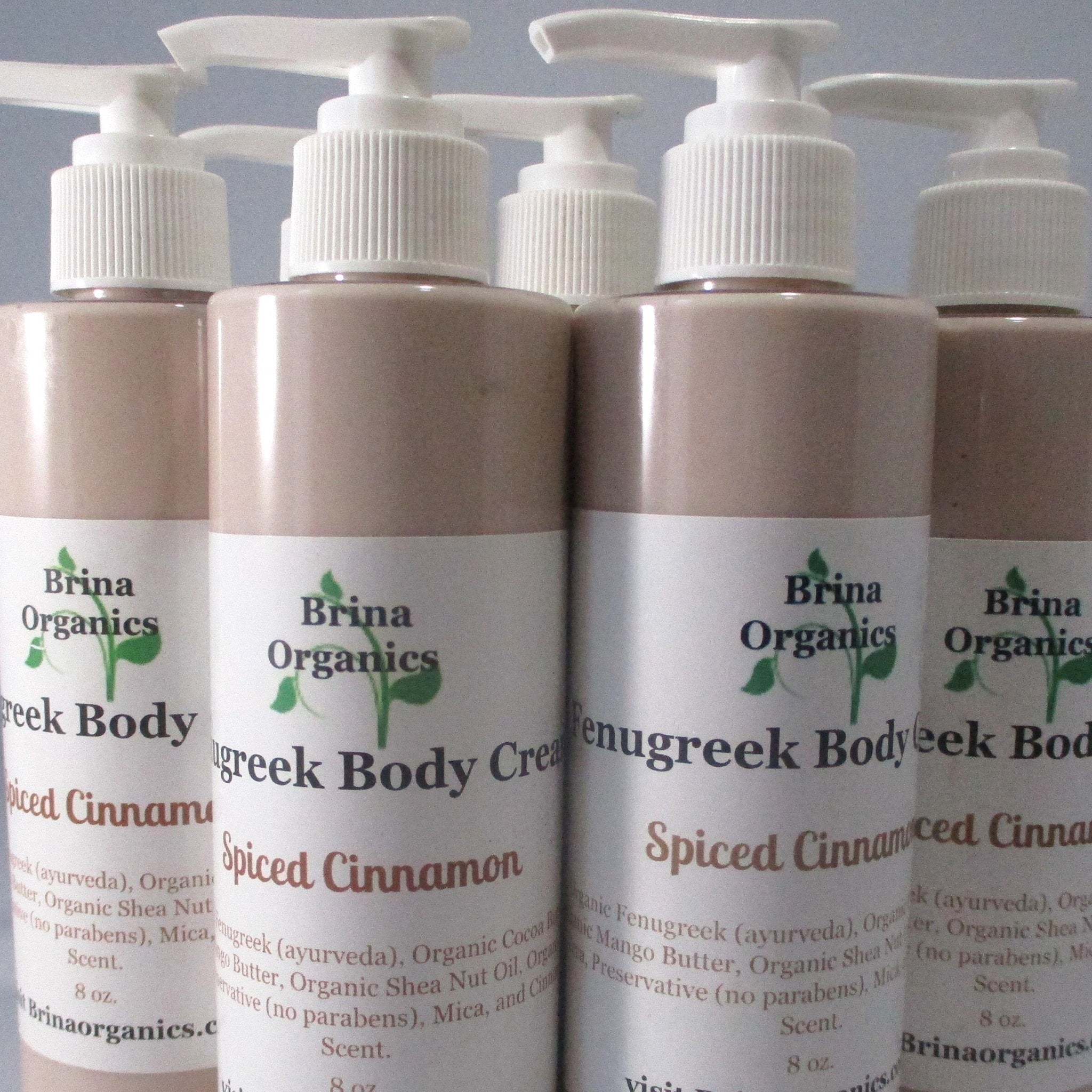 Body cream bottles with white pump tops, light brown color, and Brina Organics labels