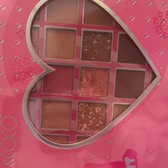 Eyeshadow palette with pink packaging, heart-shaped design, and various shades of eyeshadow