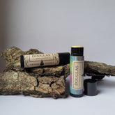 Lip balm tubes with black and patterned labels, Douglas branding visible, on wood bark