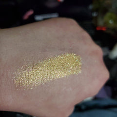Glitter eyeshadow swatch, gold with iridescent shimmer, applied to skin