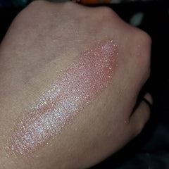 Side view of shimmering bronze eye shadow palette with embossed logo, showcasing compact size and gradient finish