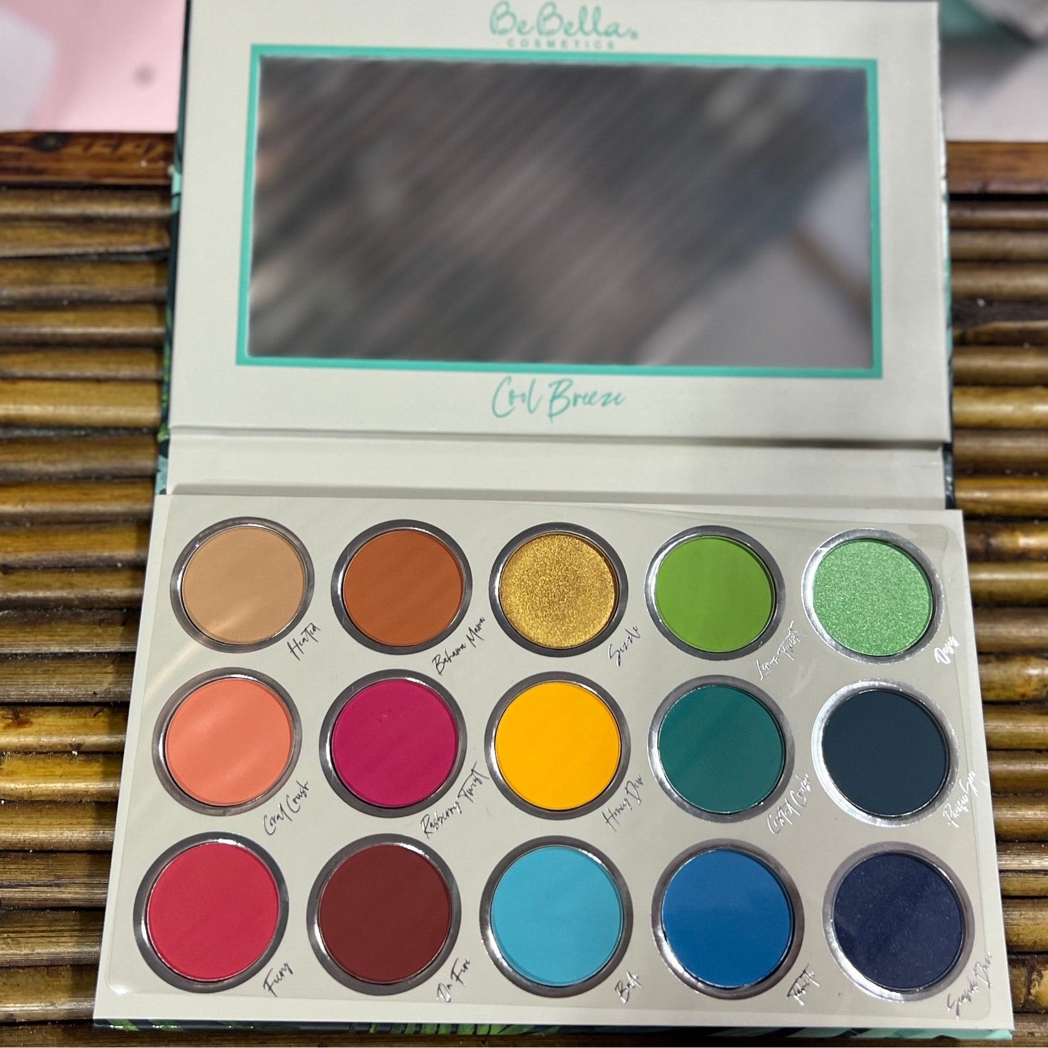 Eye shadow palette with multiple colorful eyeshadows in round pans, BeBella Cosmetics brand name visible