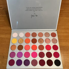 Eyeshadow palette with multiple colors, glitter, and Jaclyn Hill branding on lid