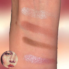 Close-up of four vibrant eyeshadow pans in warm bronze, deep plum, shimmery gold, and matte taupe shades.