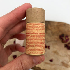 Lip balm tube in brown cardboard with text, held in hand, StardustAndStems brand visible
