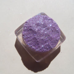 Close-up of sparkling violet and blue mineral eye shadow with glitter particles catching light
