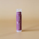 Lip balm tube with purple label, white text, and clear cap for application