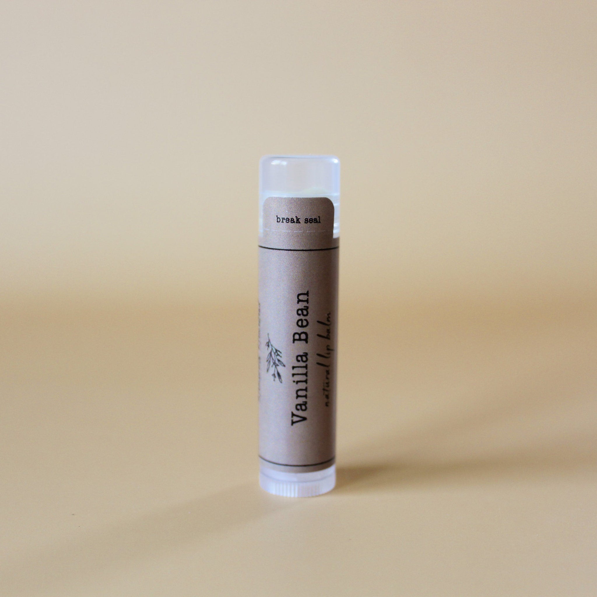 Vanilla Bean lip balm tube with brown label and clear cap, "Vanilla Bean" text visible