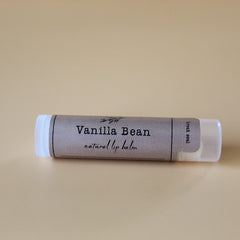 Lip balm tube with gray patterned label, white cap, and "Vanilla Bean" text