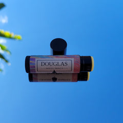 Lip balm tube with black cap, colorful patterned label, and DOUGLAS branding