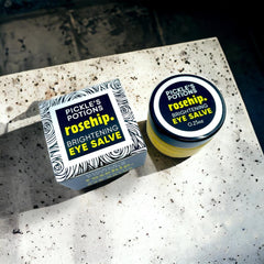 Eye salve jar and box, black and white label, yellow contents, on speckled surface