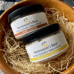 Honey Hydration Walnut Scrub jars with black lids, white labels, and "Beekeeper's Best" text in wooden bowl