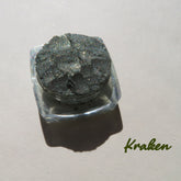 Eyeshadow pigment, dark olive green shimmer, in clear jar, Kraken brand name