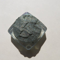 Glitter eyeshadow in dark gray with clear container, top-down view