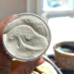 Side view of whipped tallow baby balm in white jar with gold lid, showcasing rich texture and minimalist packaging