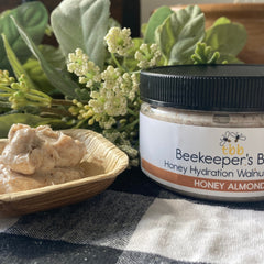 Honey hydration walnut scrub with black cap, white label, and wood bowl on checkered cloth