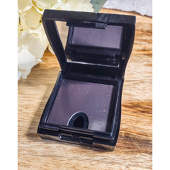 Makeup compact with black plastic case, reflective mirror, and dark eyeshadow color