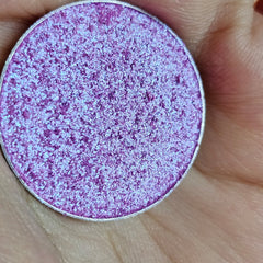 Close-up of fingers applying shimmery multichrome eyeshadow with vibrant color shift on eyelid