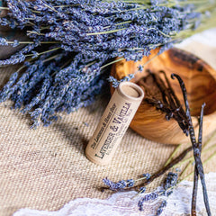 Lip balm tube with Lavender & Vanilla label, brown paper, lavender sprigs, and vanilla beans on burlap
