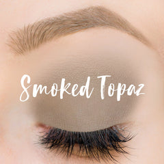 Eyeshadow in taupe color with "Smoked Topaz" text over closed eye with long lashes