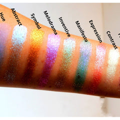 Swatches of eyeshadow in various colors, including silver, gold, purple, and red, applied to arm skin