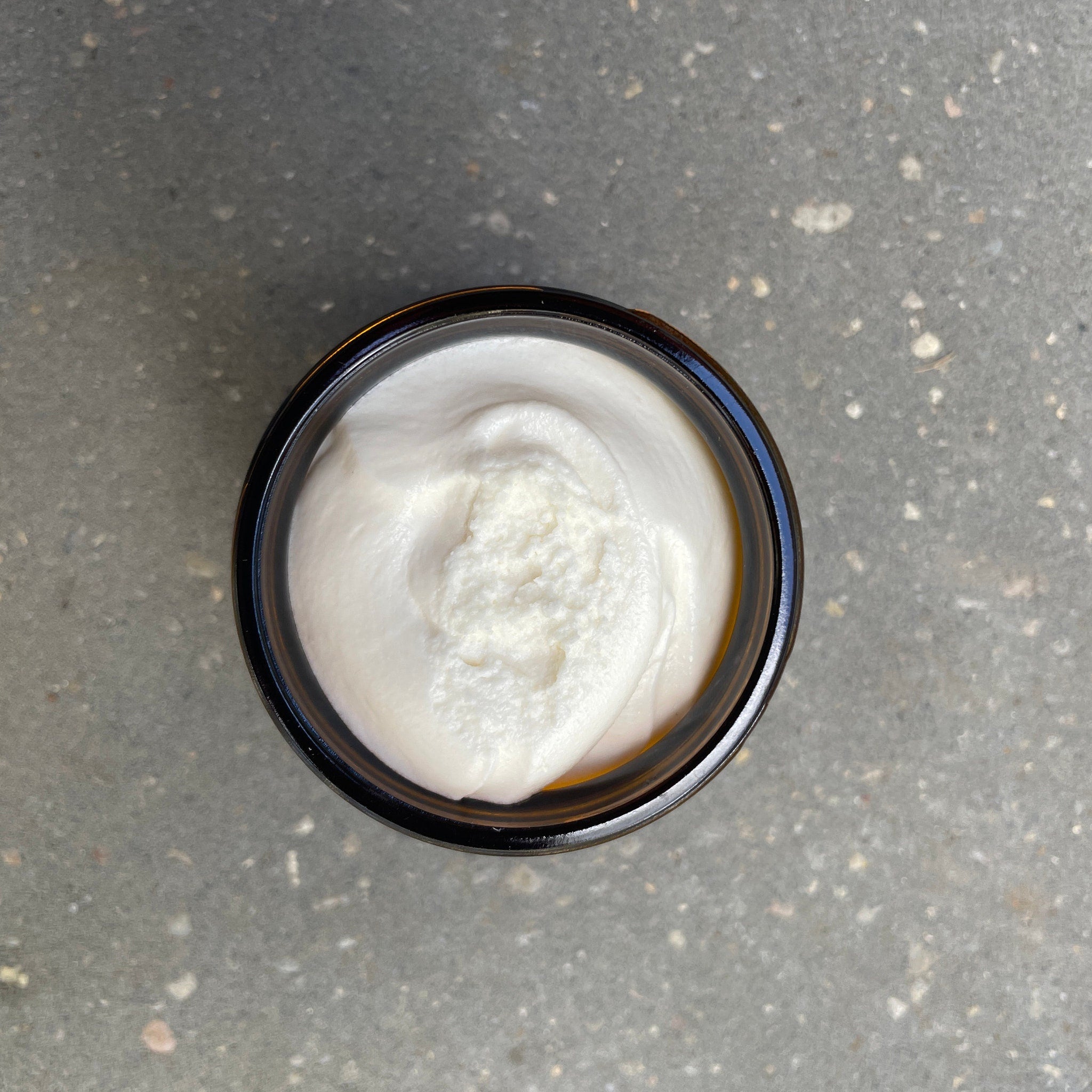 Minimalist white jar of natural moisturizing balm with gold lid on marble surface