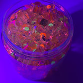 Loose stones mix with clear, orange, and green accents in a clear container, for crafts