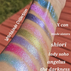 Glitter eyeshadow swatches in various colors, Witchblade Collection text visible, applied on arm