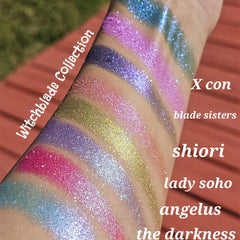 Glitter eyeshadow swatches in various colors, Witchblade Collection text visible, applied on arm