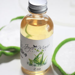 Face toner bottle with silver cap, clear glass, and Joyce Marie label, with green pads around it