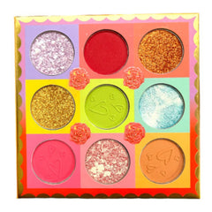 Eyeshadow palette with multiple colors, glitter, and heart details in a square box.