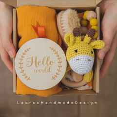 Baby gift set with yellow crochet giraffe, wooden sign, and orange fabric in a box