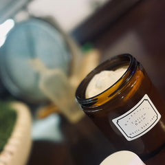 Close-up of creamy white moisturizing balm in minimalist glass jar with gold lid, texture shown on fingertips