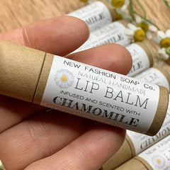 Lip balm tube with brown cardboard, white label, and visible text, held in hand