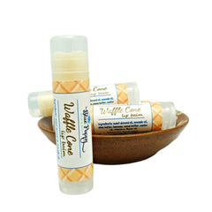 Lip balm tubes with white and orange pattern, in a brown bowl, Blue Poppy Bath brand visible