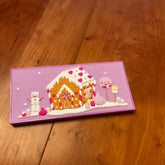 Eye makeup palette with pink, orange, and white gingerbread house design on a purple background