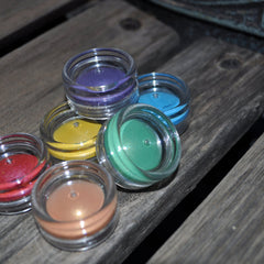 Hand applying shimmering peach mineral eyeshadow from a small jar with sifter onto eyelid