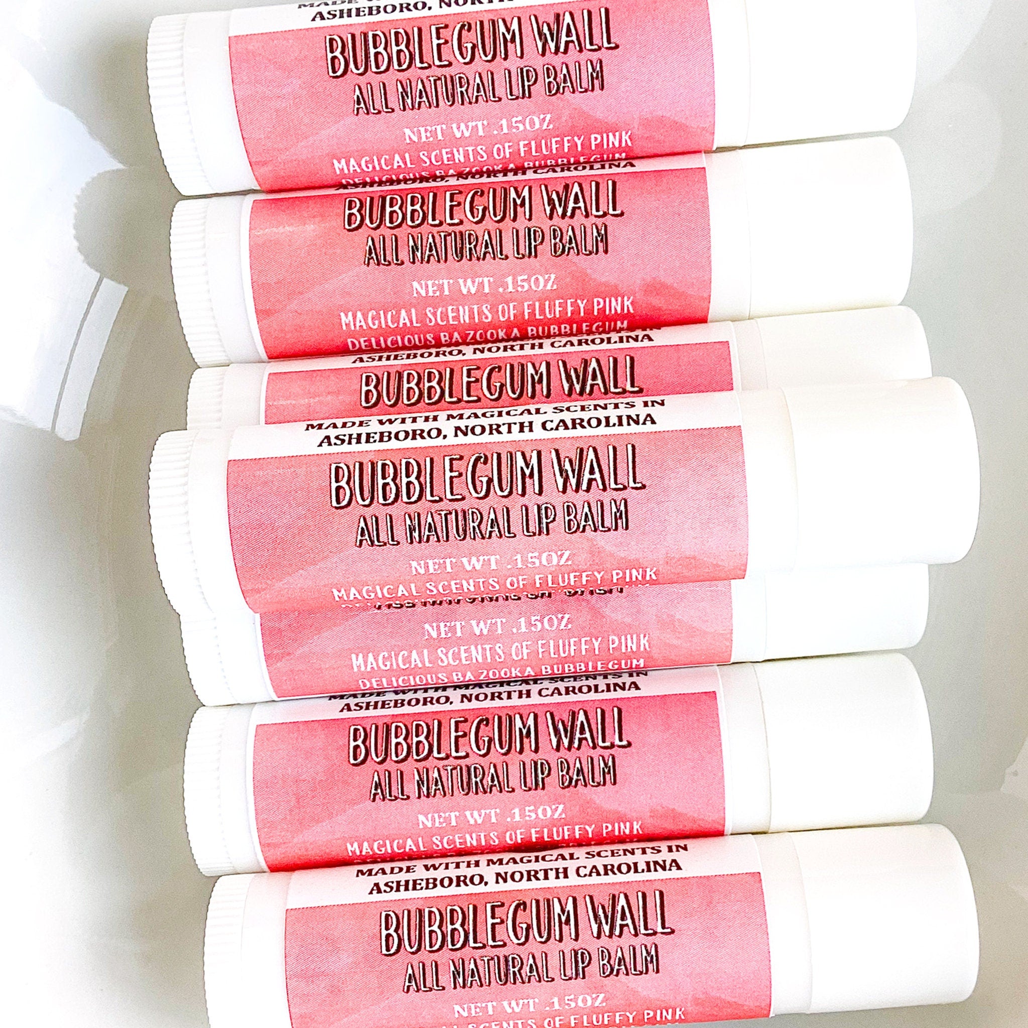 Lip balm tubes with pink label, white tube, and "Bubblegum Wall" text