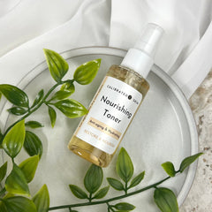 Toner bottle with white label, clear liquid, and CALIBRATED SKIN text on a plate with greenery