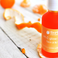 Golden-hued vitamin C serum in a sleek glass bottle with black dropper, displayed beside fresh citrus fruits